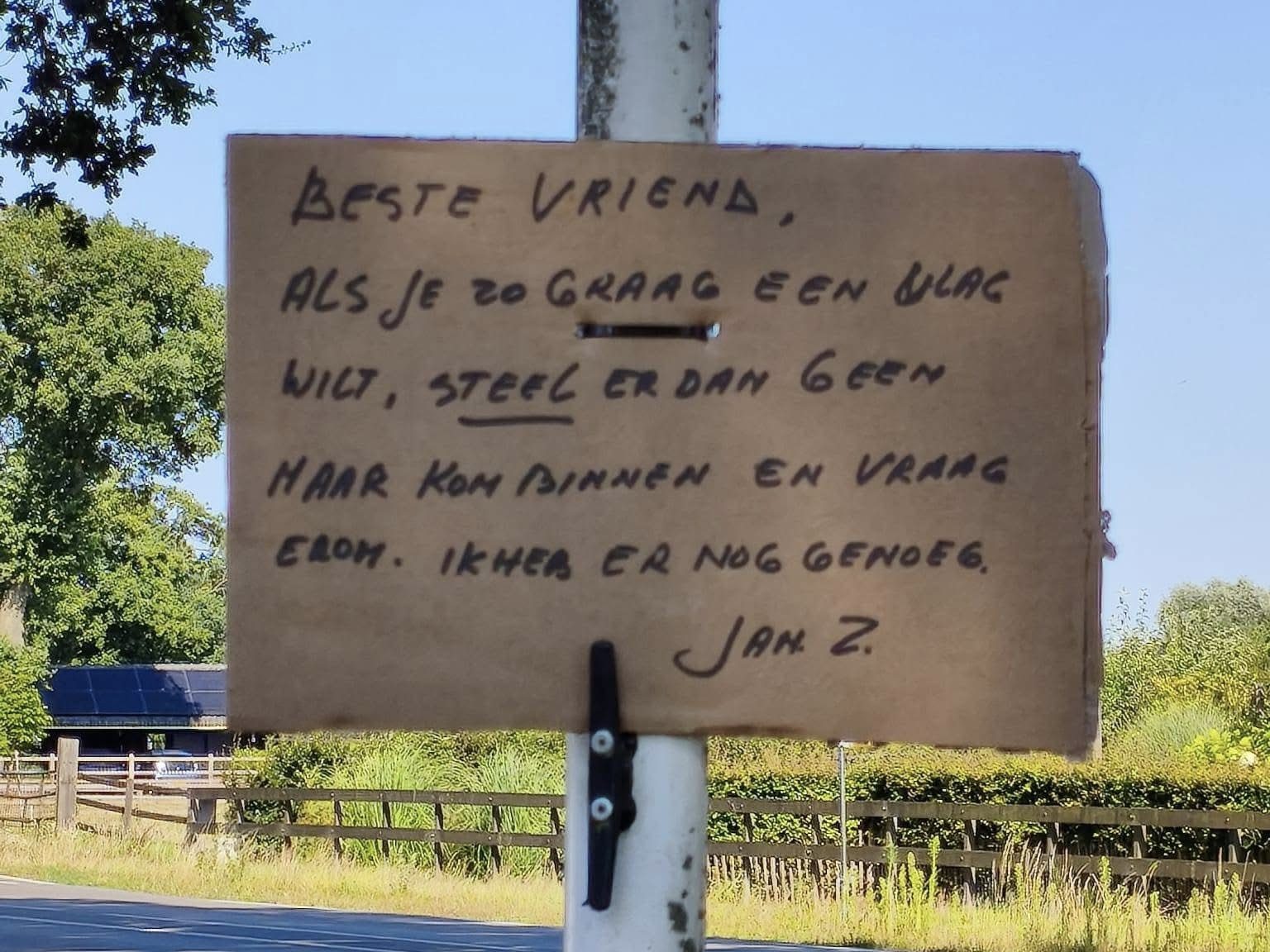 Een handgeschreven bord aan de vlaggenmast met de tekst: Beste vriend, als je zo graag een vlag wilt, steel er dan geen maar kom binnen en vraag erom. Ik heb er nog genoeg. Jan Z.