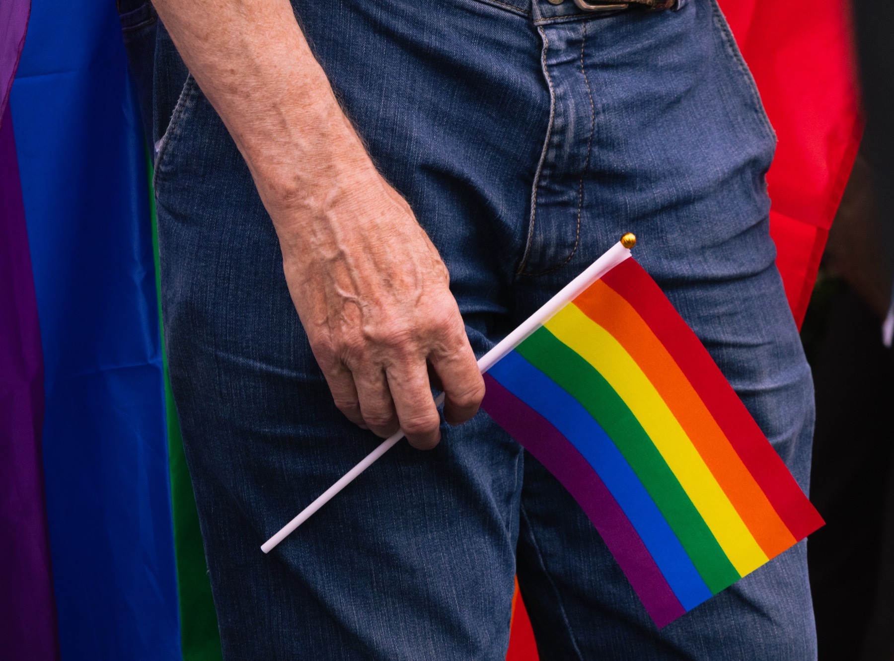Een hand houdt een klein regenboogvlaggetje omhoog