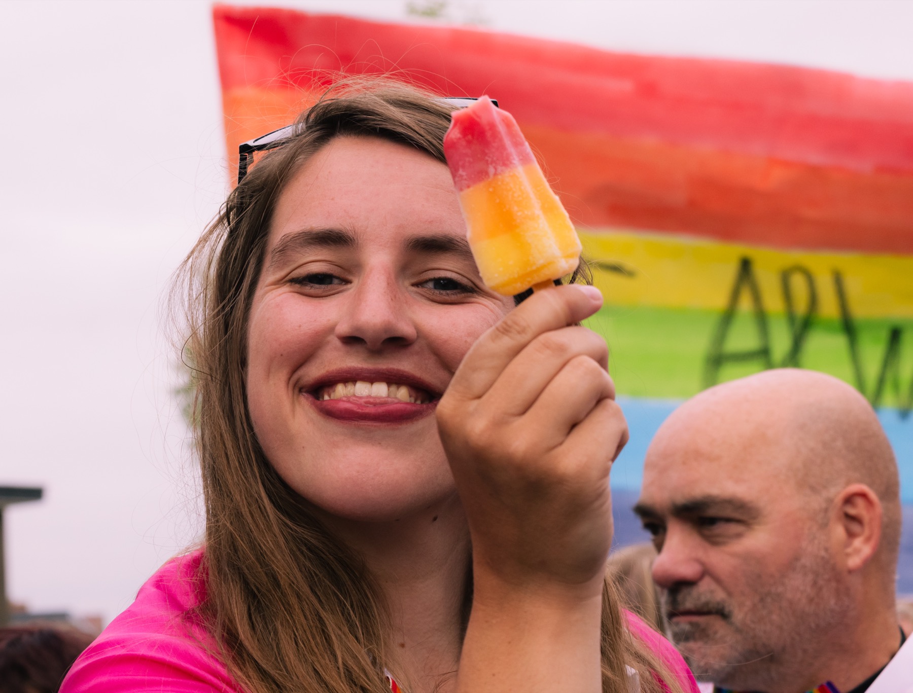 Lachende vrouw met een ijsje en een regenboogvlag